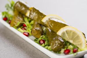 dolmé o vite le foglie con lime e Melograno semi servito nel piatto isolato su grigio sfondo superiore Visualizza di Arabo cibo foto