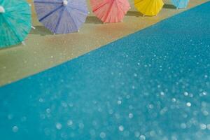 astratto spiaggia con luccichio carta sabbia e acqua e cocktail ombrelli foto