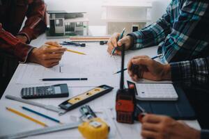 ingegnere persone incontro Lavorando e puntamento a un' disegni nel ufficio per discutere. ingegneria utensili e costruzione concetto. foto