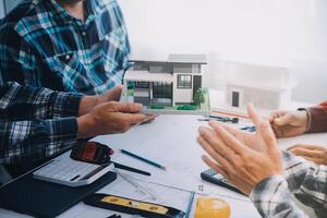 ingegnere persone incontro Lavorando e puntamento a un' disegni nel ufficio per discutere. ingegneria utensili e costruzione concetto. foto