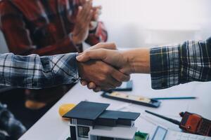 architetto e ingegnere costruzione lavoratori tremante mani mentre Lavorando per lavoro di squadra e cooperazione concetto dopo finire un accordo nel il ufficio costruzione luogo, successo collaborazione concetto foto