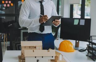 costruzione e struttura concetto di ingegnere o architetto incontro per progetto Lavorando con compagno e ingegneria utensili su modello edificio e planimetria nel Lavorando luogo, contrarre per tutti e due aziende. foto