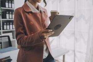 il ritratto di una giovane donna asiatica libera professionista sta lavorando sul tablet del computer in un ufficio moderno. fare un rapporto di analisi contabile dati di investimento immobiliare, concetto di sistemi finanziari e fiscali. foto