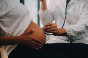 femmina medico è controllo incinta donna con stetoscopio. concetto cura per incinta donna foto