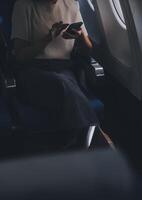 attraente asiatico femmina passeggeri di aereo seduta nel confortevole posto a sedere mentre Lavorando il computer portatile e tavoletta con finto su la zona utilizzando senza fili connessione. viaggio nel stile, opera con adornare. foto