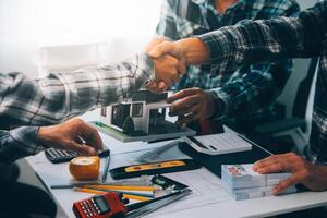 architetto e ingegnere costruzione lavoratori tremante mani mentre Lavorando per lavoro di squadra e cooperazione concetto dopo finire un accordo nel il ufficio costruzione luogo, successo collaborazione concetto foto