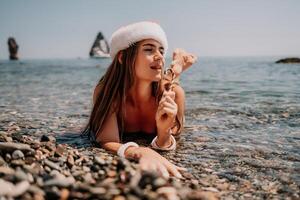 donna viaggio mare. contento turista godere assunzione immagine su il spiaggia per ricordi. donna viaggiatore nel Santa cappello sembra a telecamera su il mare baia, condivisione viaggio avventura viaggio foto