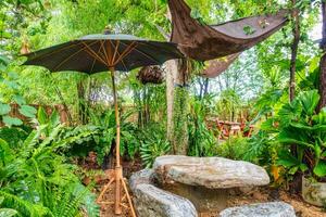 naturale roccia tavolo, posto a sedere e parasole nel tropicale giardino su Giardino dietro la casa foto