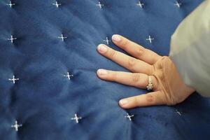 donne mano toccante e urgente ortopedico materasso su letto. foto