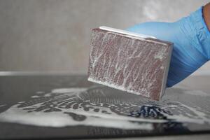 superiore Visualizza pulizia un' ceramica elettrico stufa con un' metallo raschietto. foto