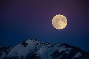 ai generato immagine stock pieno Luna brilla brillantemente contro il fondale di il notte cielo foto