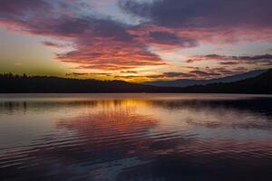 ai generato ipnotizzante tramonto vernici il cielo sopra il tranquillo lago foto