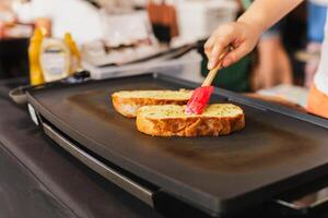 donna cucinando aglio pane con e erbe aromatiche su ferro padella. foto