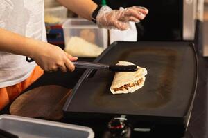 donna preparazione fresco Quesadilla su nero griglia a Locale cibo mercato. foto