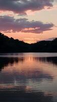 ai generato radiante tramonto calchi tonalità di oro e rosa al di sopra di tranquillo lago verticale mobile sfondo foto