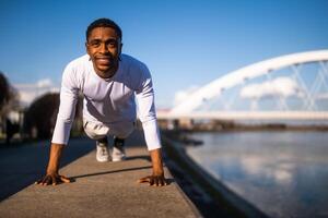 giovane afroamericano uomo è esercizio nel il città. lui è fare sollevamento. foto