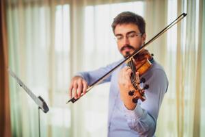 uomo giocando violino a casa. lui è praticante per vivere prestazione. foto