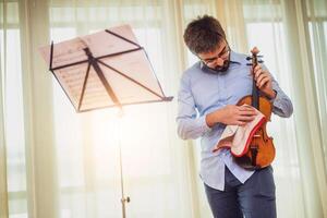 uomo giocando violino a casa. lui è pulizia il suo strumento. foto