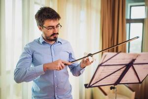 uomo giocando violino a casa. lui è pulizia il suo strumento. foto