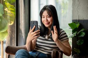 un' sorridente asiatico donna è parlando su un' chiamata su sua smartphone con sua amico. foto