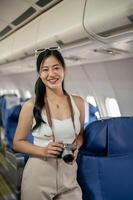 un attraente asiatico femmina passeggeri sta nel il corridoio su un' aereo, sorridente a il telecamera. foto