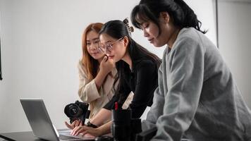 un' professionale asiatico femmina fotografo è Lavorando con sua assistenti nel un' servizio fotografico studio. foto