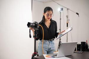 un' freddo, attraente asiatico femmina fotografo produttore è Lavorando nel un' tiro studio. foto