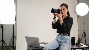 un' femmina fotografo è assunzione fotografie, Tenere un' telecamera vicino sua viso, Lavorando nel un' studio. foto