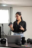 professionale asiatico femmina fotografo è preparazione sua telecamera per un' servizio fotografico, Lavorando nel un' studio foto