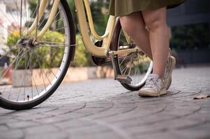 un' ritagliata tiro di un' donna di gambe a piedi e spingendo un' bicicletta su il strada nel il città. foto