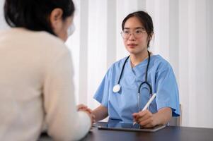 un' professionale asiatico femmina medico è Lavorando nel sua ufficio, parlando e dando consigli per un' paziente. foto