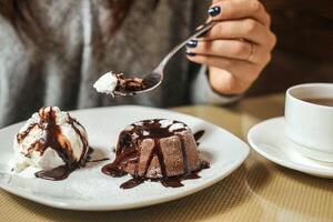 donna godendo un' torta fetta con ghiaccio crema e cioccolato salsa foto