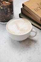 caffè tazza lungo con un' pila di libri su un' di legno tavolo foto