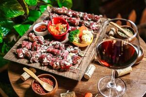 abbondante di legno tavolo con assortito cibo e un' bicchiere di vino foto