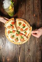 persona Tenere Pizza su di legno tavolo foto