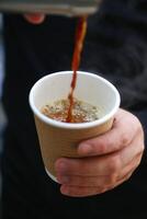 persona scrosciante caldo caffè in un' bianca ceramica tazza foto