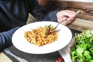 persona Tenere forchetta nel ciotola di pasta foto