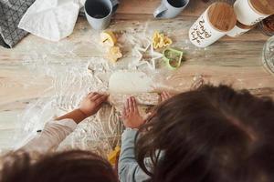 concezione della cucina. vista dall'alto dei bambini che imparano a preparare il cibo dalla farina con speciali strumenti formati foto