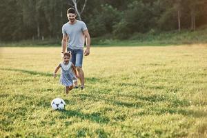papà entusiasta insegna alla figlia come giocare al suo gioco preferito. è il calcio e anche le bambine possono giocarci foto
