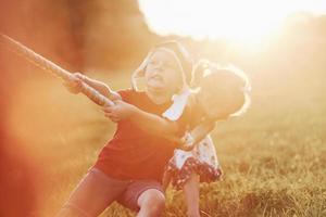 sento la forza nelle mie mani. questo è un tiro alla fune con papà sulla bellissima erba di una calda giornata di sole foto