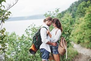 tenerezza. la giovane coppia ha deciso di trascorrere le proprie vacanze in modo attivo vicino al lago sullo sfondo foto
