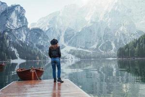 boschi e lago di cristallo. donna con cappello nero che si gode un maestoso paesaggio di montagna vicino al lago con barche