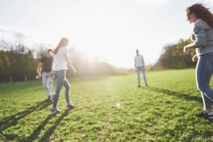 un gruppo di amici in abbigliamento casual gioca a calcio all'aria aperta. le persone si divertono e si divertono. riposo attivo e tramonto panoramico foto