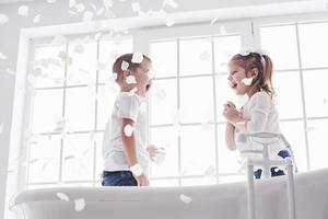 bambino che gioca con petali di rosa nel bagno di casa. bambina e ragazzo fawing divertimento e gioia insieme. il concetto di infanzia e la realizzazione di sogni, fantasia, immaginazione foto