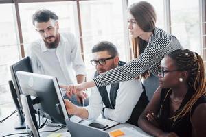 giovani dipendenti seduti in ufficio al tavolo e utilizzando un laptop, un concetto di incontro di brainstorming di lavoro di squadra. foto