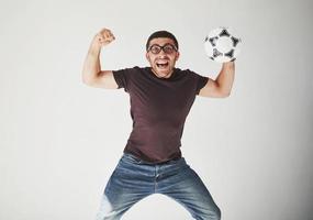 appassionato di calcio eccitato con un pallone da calcio isolato su sfondo bianco. salta è felice ed esegue vari trucchi di tifo per la sua squadra del cuore