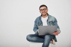 bel giovane con laptop e controlla il suo orario su sfondo bianco foto