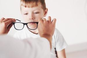 proviamo questo modello. dottore che dà al bambino nuovi occhiali neri per la sua vista foto