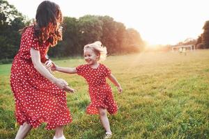 tramonto dorato dietro. giovane madre con sua figlia che trascorrono del tempo fuori in un posto così bello foto