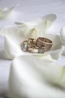 d'oro anelli su un' bianca petali di Rose. foto